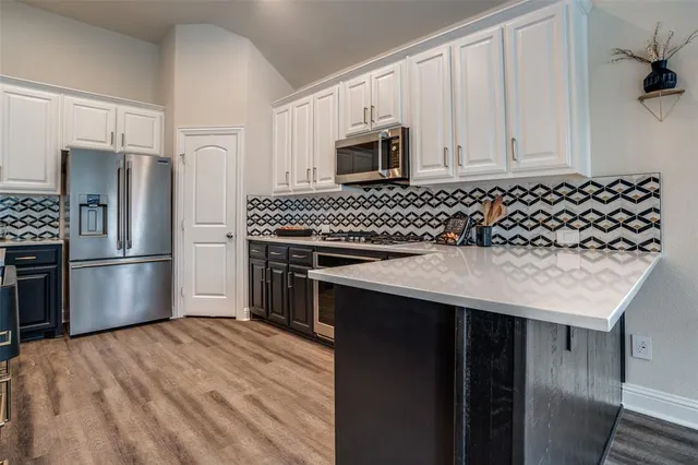 a kitchen with stainless steel appliances granite countertop a refrigerator a stove and white cabinets