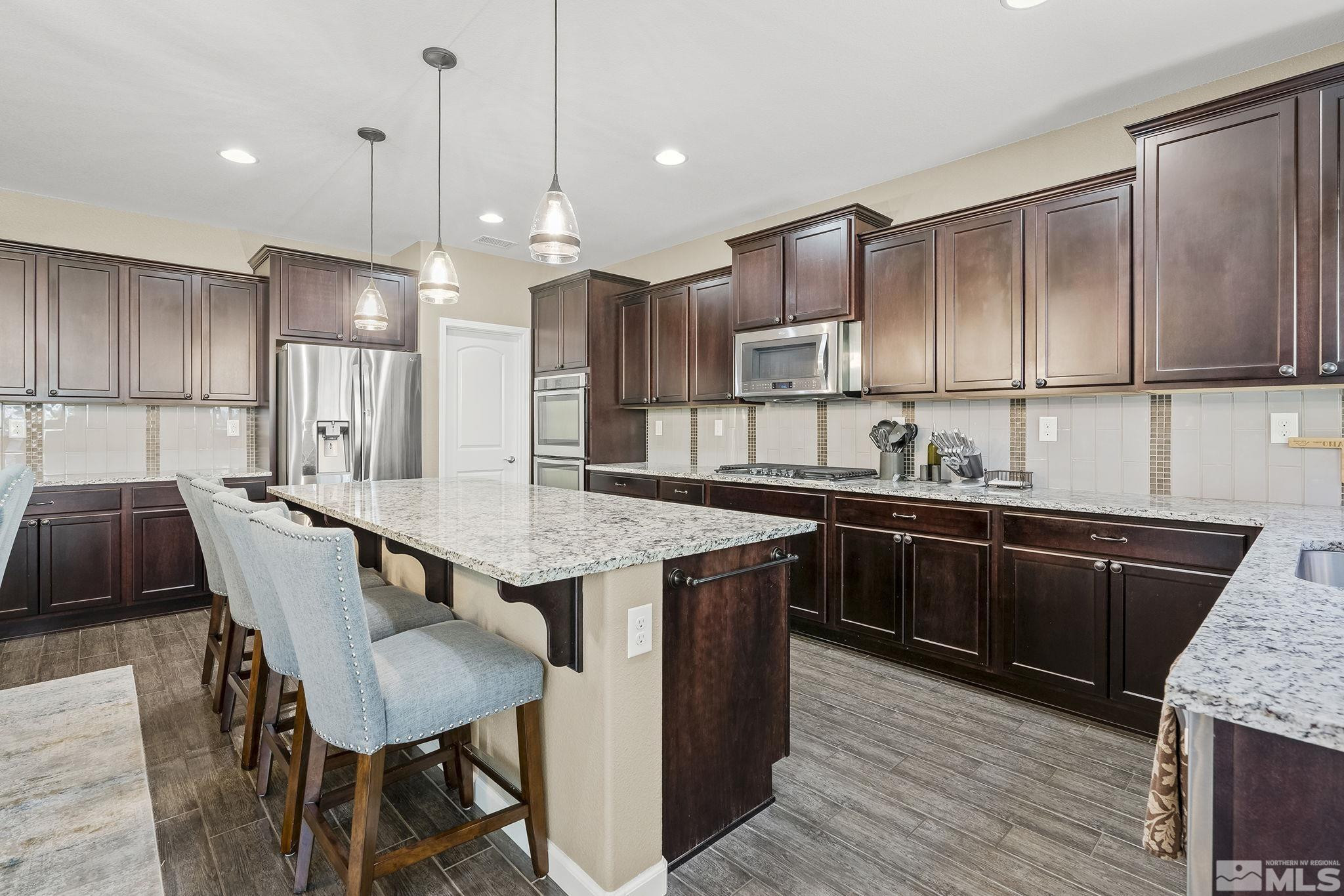1653 Crescent Pointe Court Reno, NV 89523 - Photo 12 of 39 a kitchen with granite countertop a table chairs a sink dishwasher refrigerator and cabinets
