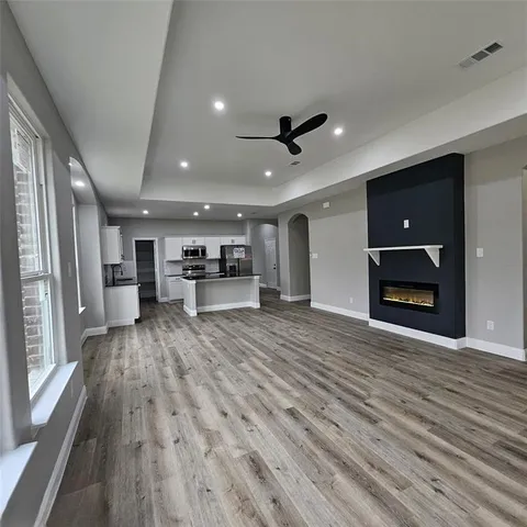 a view of a livingroom with a flat screen tv wooden floor and a ceiling fan