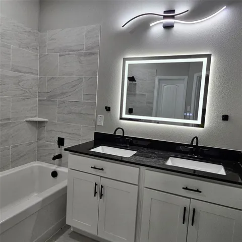a bathroom with a sink a bathtub a mirror and vanity