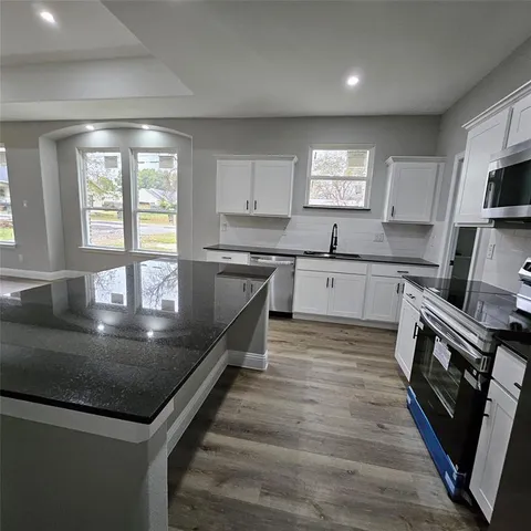 a large kitchen with stainless steel appliances granite countertop a sink window and cabinets