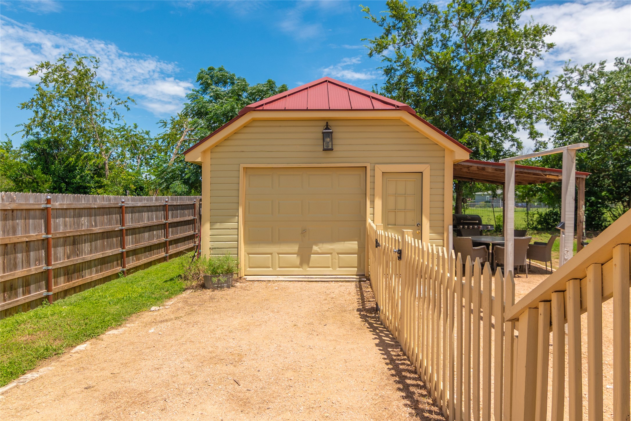 204 Prim Rose Road Blanco, TX 78606 - Photo 37 of 40 Detached outbuilding with a metal roof is bordered by wooden and picket fences.