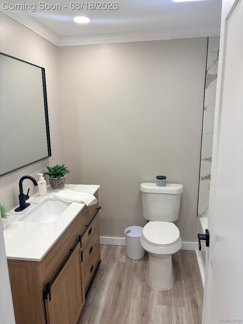 32563 Sutton Road New Baltimore, MI 48047 - Photo 24 of 43 Modern bathroom featuring a wood-finish vanity with white countertop, integrated sink, and matte black faucet