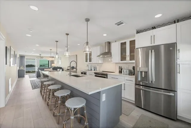 a kitchen with stainless steel appliances a refrigerator a stove a sink and white cabinets