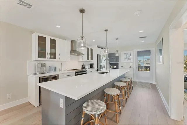 a kitchen with stainless steel appliances a stove a sink a kitchen island with chairs and wooden floor