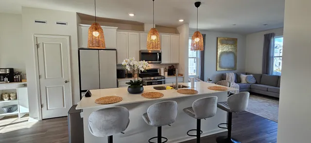 a dining room with stainless steel appliances kitchen island granite countertop a refrigerator a sink a dining table and chairs with wooden floor