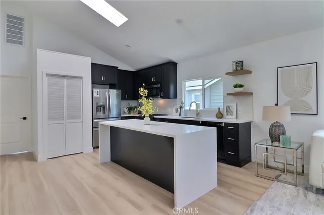 a kitchen with stainless steel appliances kitchen island granite countertop a refrigerator and a sink