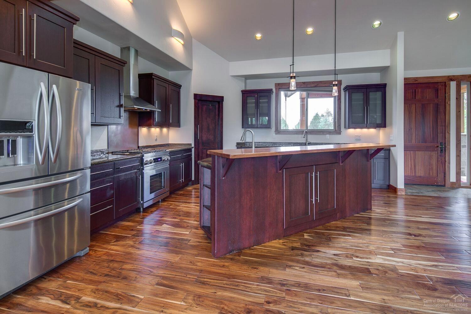 62855 Dickey Road Bend, OR 97701 - Photo 11 of 25 a large kitchen with stainless steel appliances wooden floors and wooden cabinets