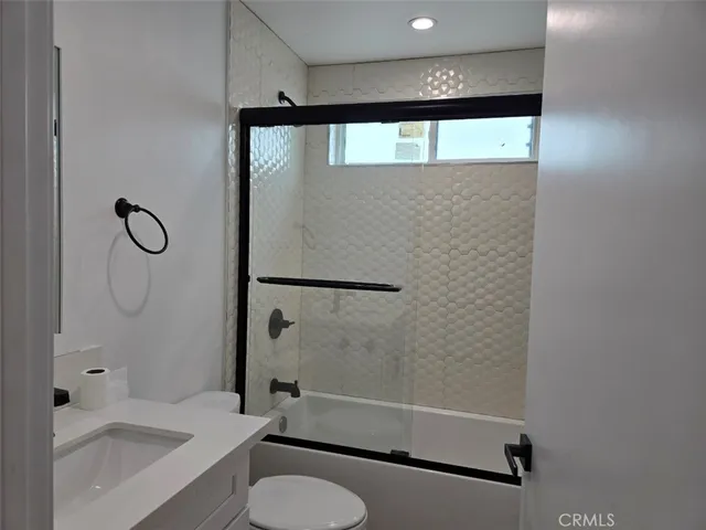 a bathroom with a granite countertop bathtub shower sink vanity and toilet