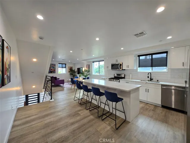 a kitchen with lots of wooden furniture appliances and dining table