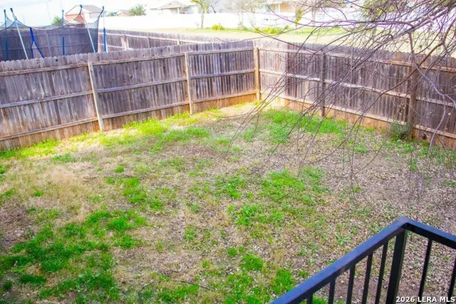 a view of a backyard with a large tree and wooden fence