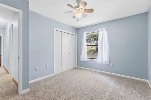 an empty room with a window and a fan
