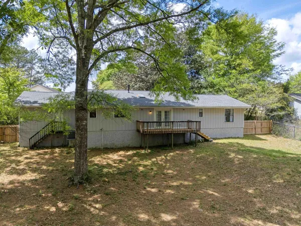 a backyard of a house with wooden fence and large trees