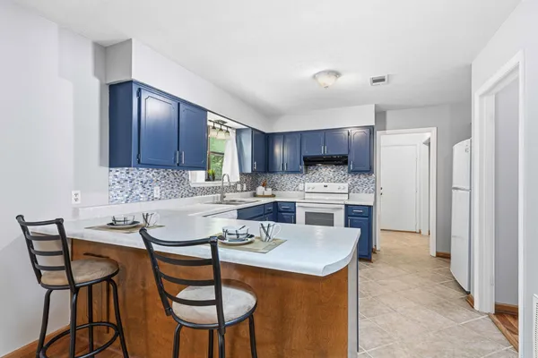 a kitchen with kitchen island granite countertop wooden cabinets and a refrigerator