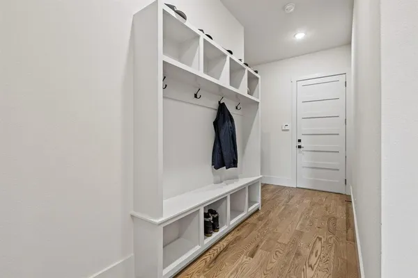 a hallway with white cabinets and wooden floor
