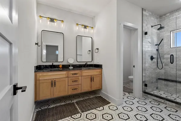 a bathroom with a double vanity sink mirror and shower