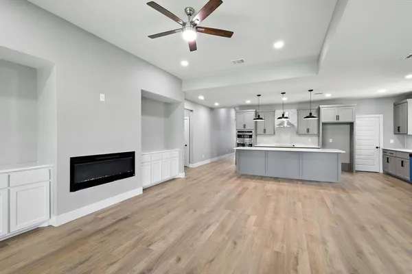 a living room with stainless steel appliances kitchen island granite countertop a refrigerator a stove a sink and a oven with wooden floor
