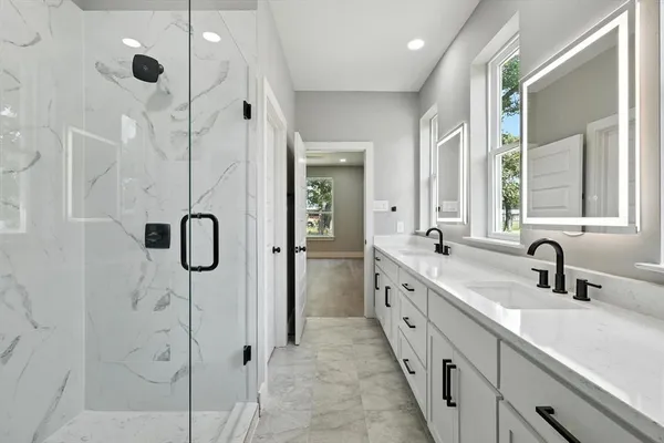 a bathroom with a double vanity sink a mirror and shower