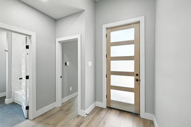 an empty room with wooden floor closet and windows
