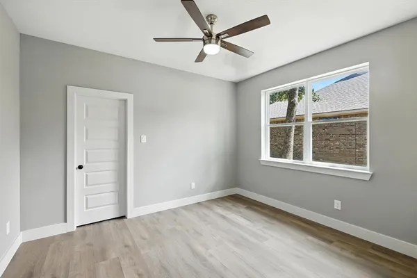 an empty room with a window and a ceiling fan