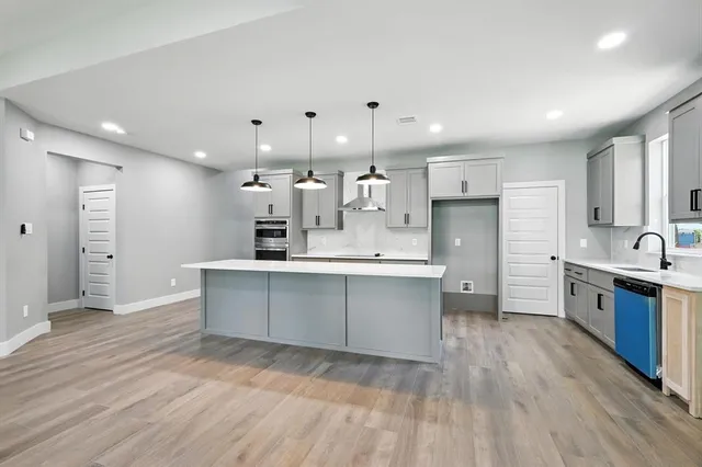 a large white kitchen with kitchen island a sink a center island stainless steel appliances and a cabinets