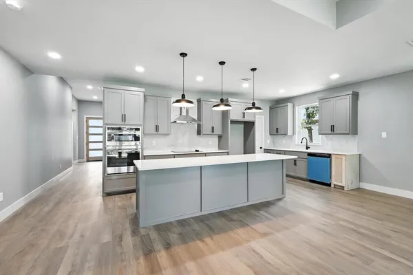 a large white kitchen with lots of counter space wooden floor and stainless steel appliances