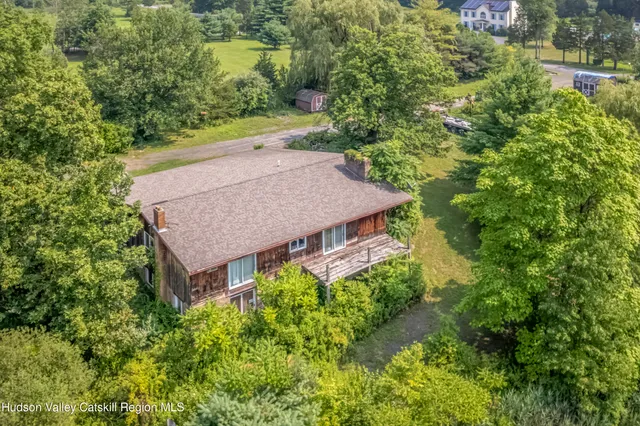 an aerial view of a house with yard and trees all around