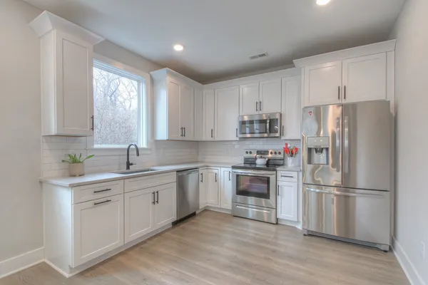 a kitchen with cabinets stainless steel appliances a sink and a window