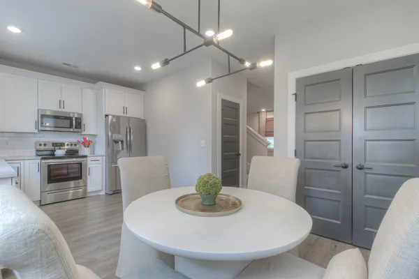 a kitchen with stainless steel appliances a dining table a microwave a refrigerator and chairs