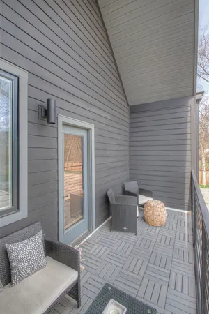 a balcony with wooden floor table and chairs