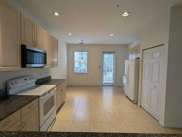 a kitchen with granite countertop a stove a sink and a refrigerator