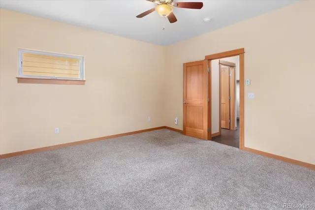 an empty room with a ceiling fan and window