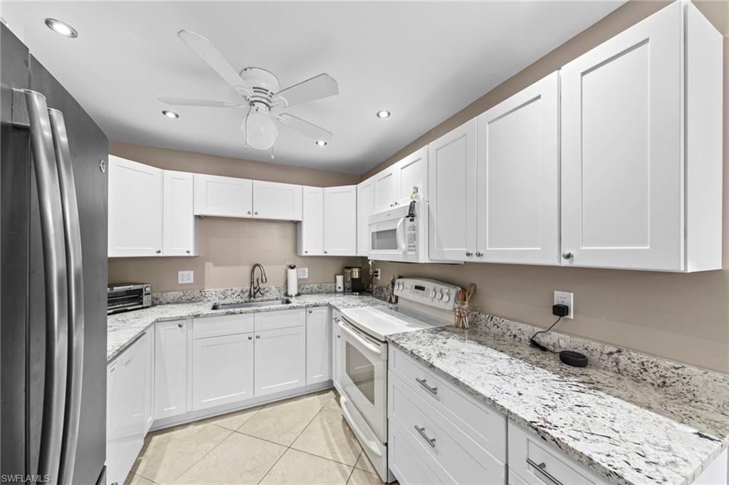 180 Harrison Road, Unit G4 Naples, FL 34112 - Photo 12 of 46 a kitchen with granite countertop a sink stainless steel appliances and white cabinets