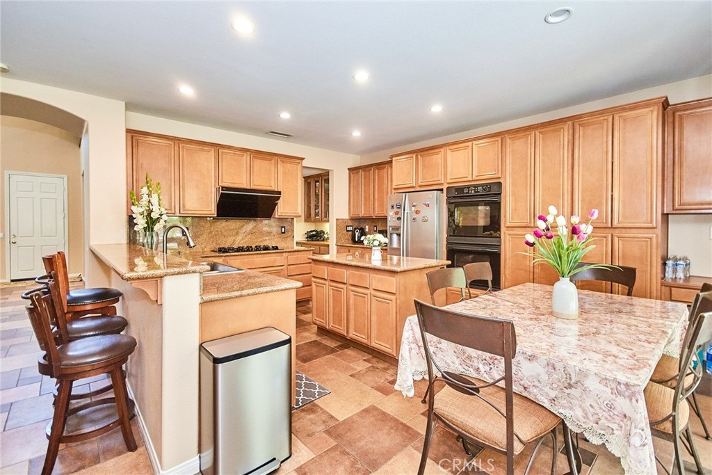 12430 Split Rein Drive Rancho Cucamonga, CA 91739 - Photo 15 of 29 a kitchen with a refrigerator and a stove top oven with wooden chairs