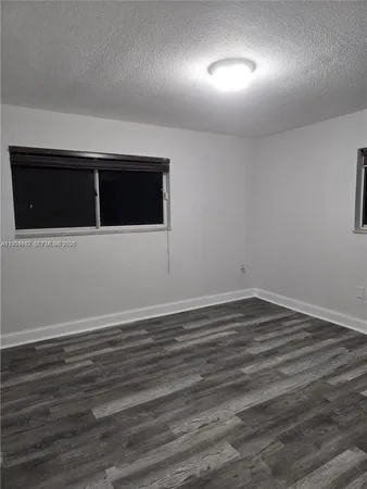 a view of an empty room with wooden floor and windows
