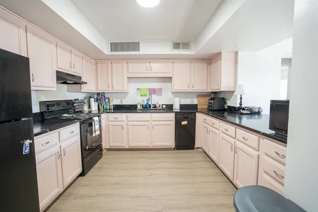 a kitchen with stainless steel appliances granite countertop white cabinets granite counter tops a sink a stove a refrigerator and white cabinets