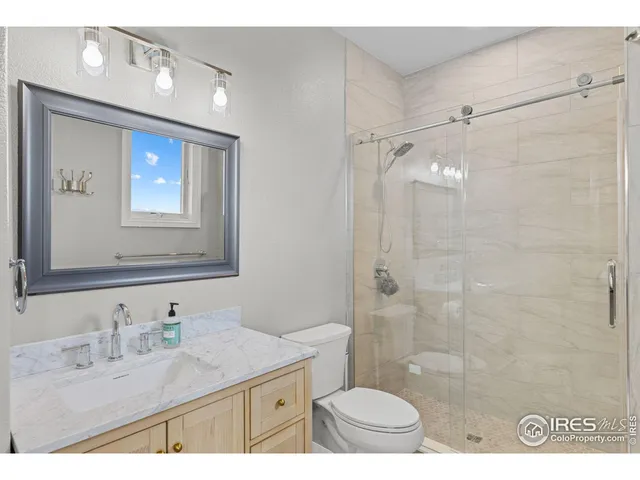 a bathroom with a granite countertop sink mirror toilet and shower