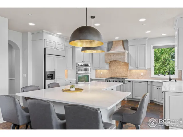 a kitchen with kitchen island granite countertop a sink a stove a refrigerator and a dining table with wooden floor