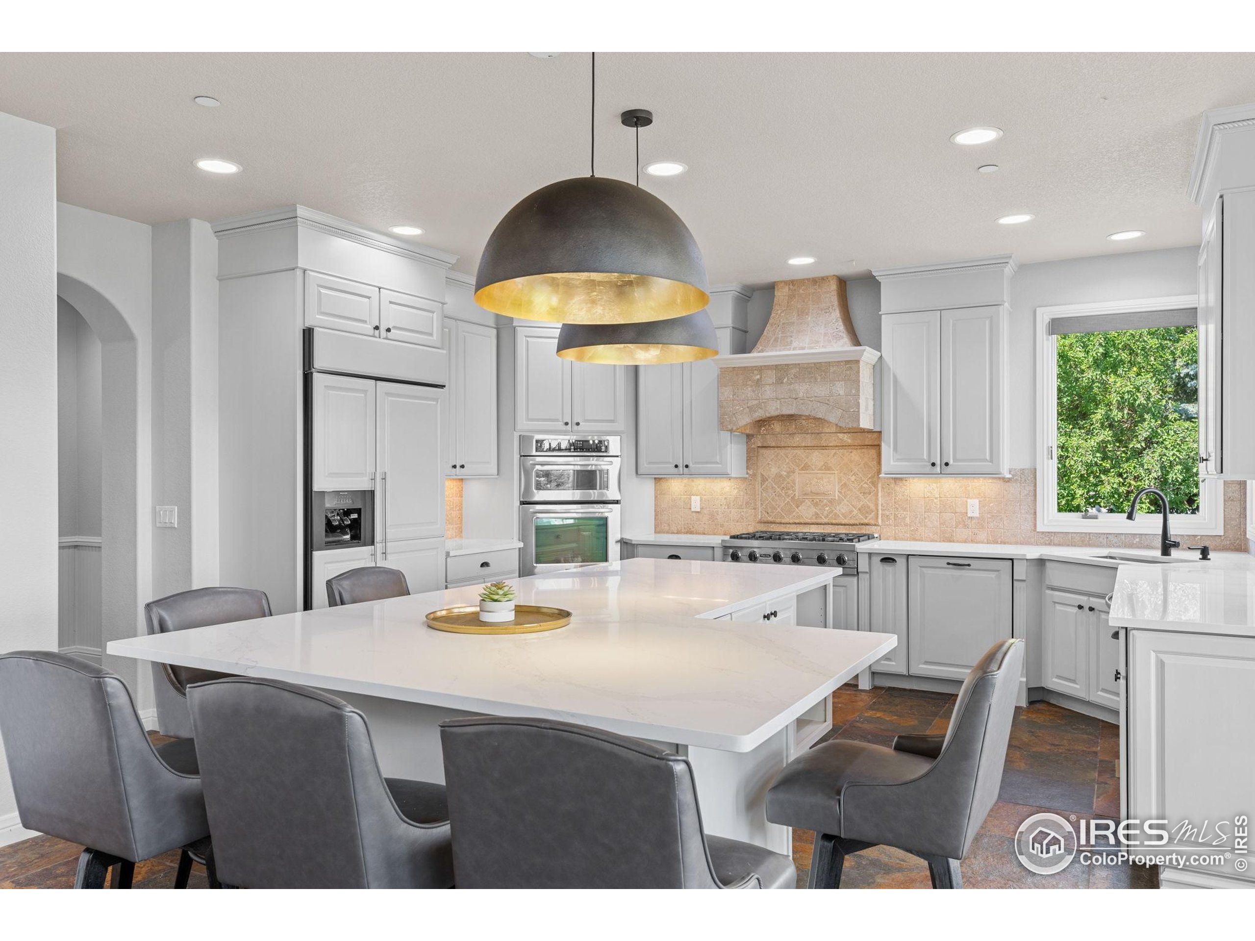 6557 Legend Ridge Trail Niwot, CO 80503 - Photo 10 of 42 a kitchen with kitchen island granite countertop a sink a stove a refrigerator and a dining table with wooden floor