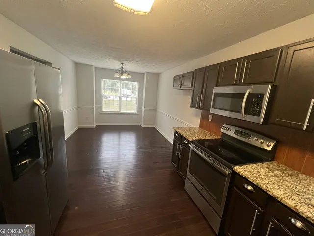 a kitchen with granite countertop a stove refrigerator and microwave