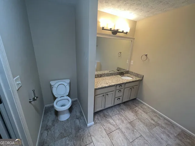 a bathroom with a granite countertop toilet sink and mirror