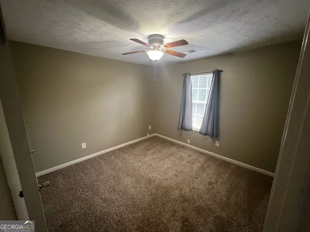 an empty room with a chandelier fan and windows