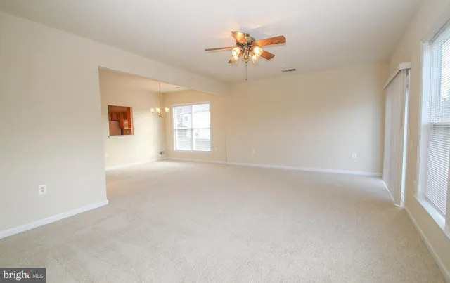 en empty room with windows and chandelier fan