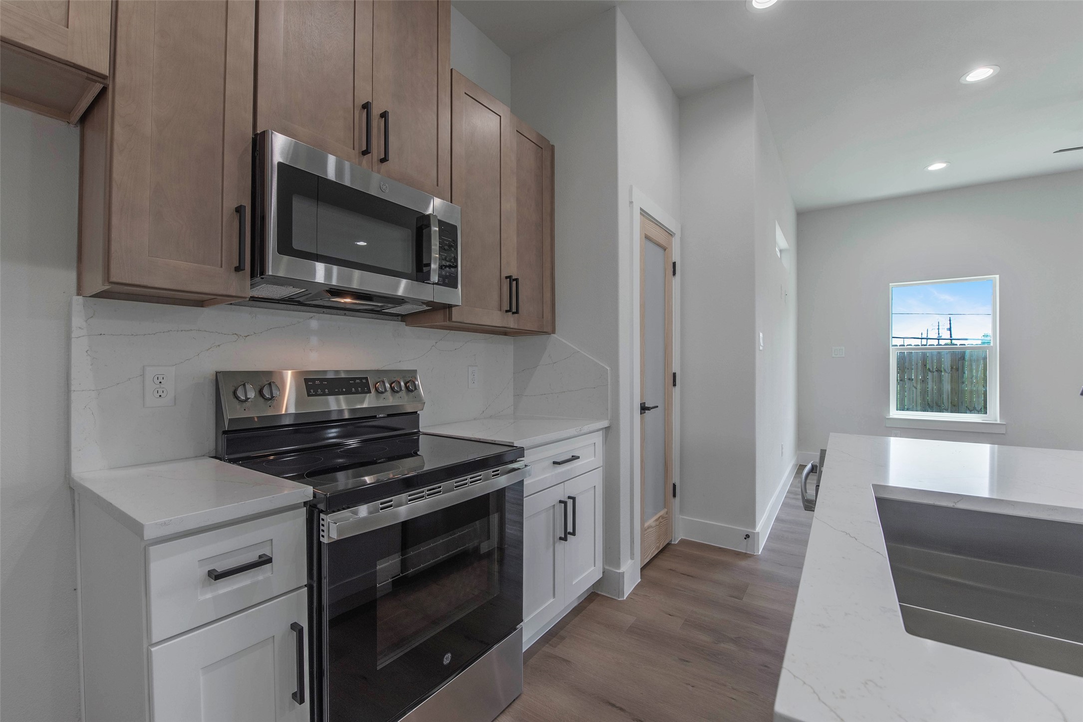 9311 Jutland Road Houston, TX 77033 - Photo 7 of 28 The kitchen is fully equipped with quartz countertops, a cooking range, microwave, and dishwasher, combining style and functionality for everyday living.