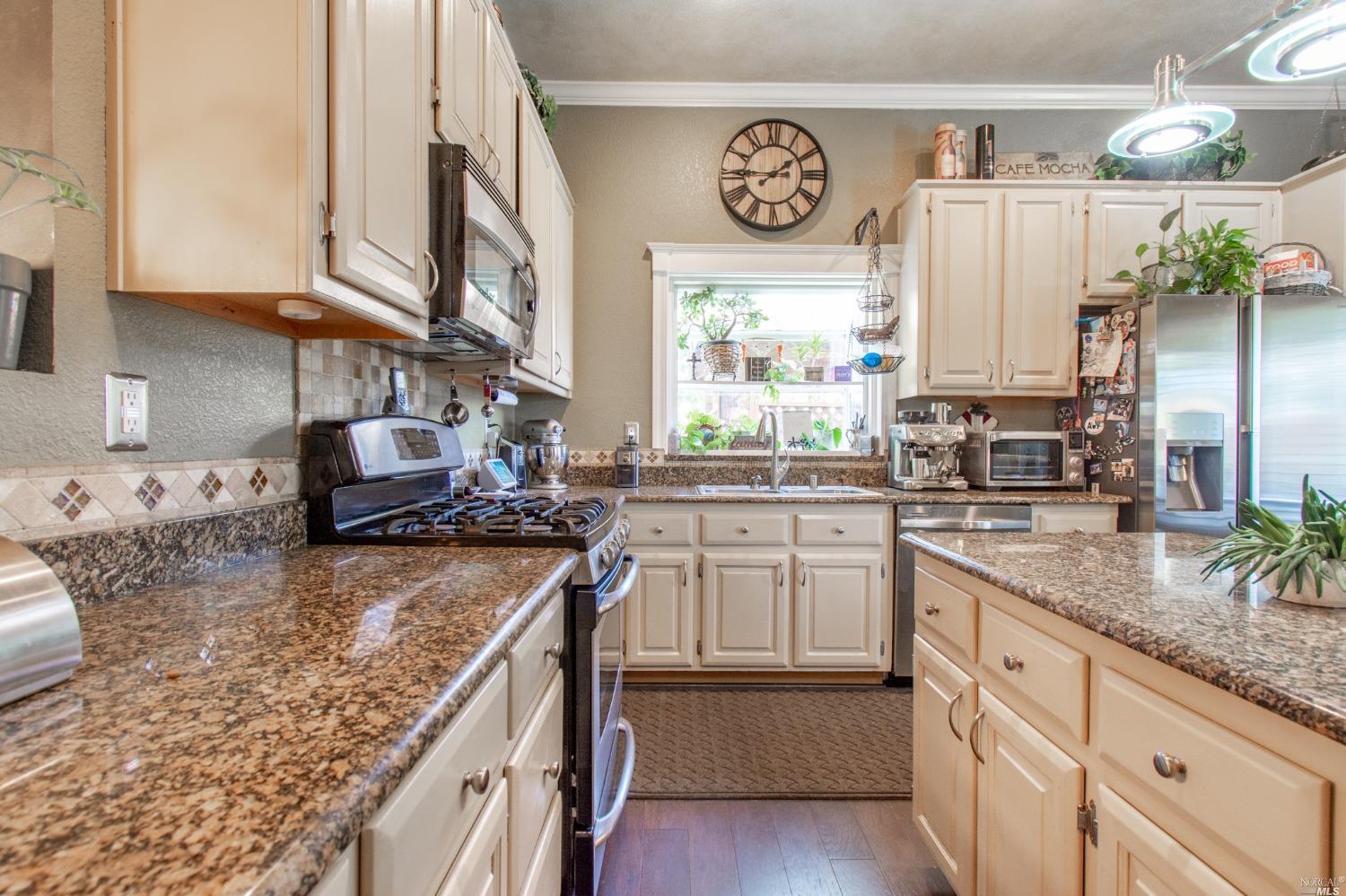 a kitchen with stainless steel appliances granite countertop a stove a sink and a white cabinets