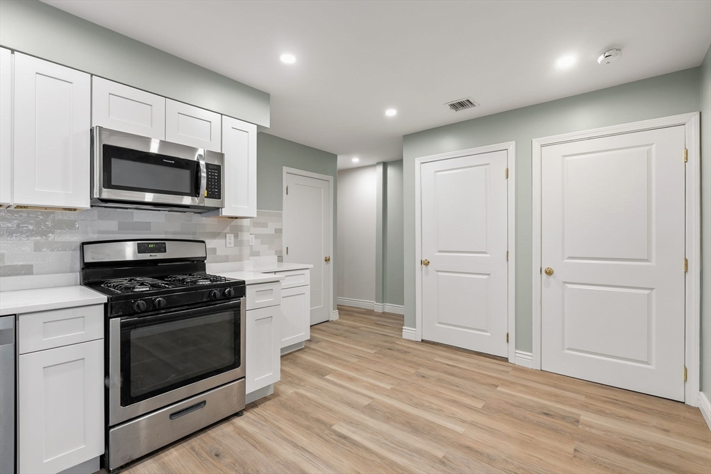 8 1/2 Intervale Street, Unit 10 1/2 Quincy, MA 02169 - Photo 3 of 16 a kitchen with granite countertop wooden cabinets stainless steel appliances and a wooden floor