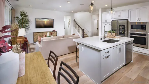 a kitchen with stainless steel appliances a stove a sink a microwave a refrigerator and white cabinets with wooden floor