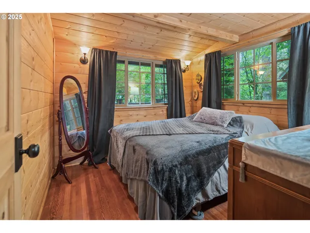 a bedroom with a bed a dresser and windows