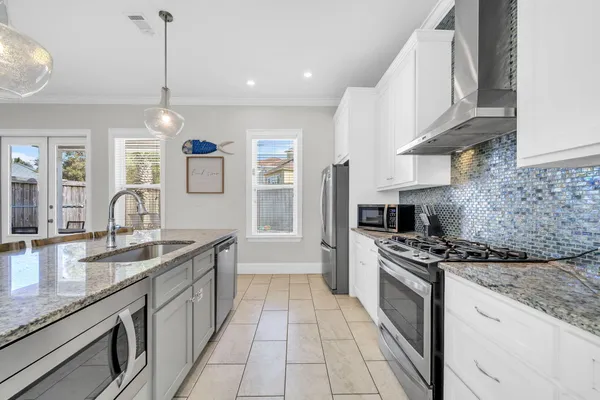 a view of a kitchen counter top space a sink stainless steel appliances and a chandelier