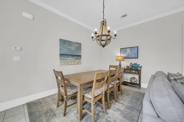 a dining room with chandelier and wooden floor